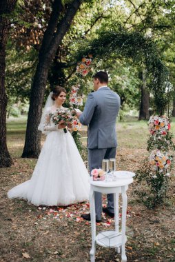 Bir adamla bir kızın düğün seremonisi Orman yolunda bir kemerin arka planına karşı