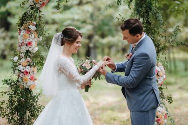 Bir adamla bir kızın düğün seremonisi Orman yolunda bir kemerin arka planına karşı