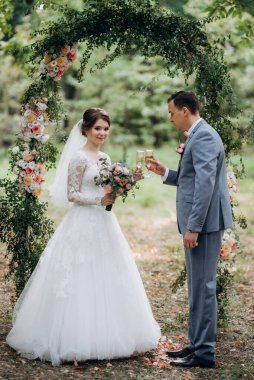 Bir adamla bir kızın düğün seremonisi Orman yolunda bir kemerin arka planına karşı