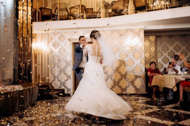 Gelin ve damadın ilk düğün dansı gün batımında restoranın içinde.