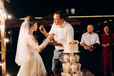 newlyweds happily cut, laugh and taste the wedding cake