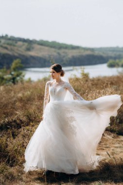bride blonde girl with a bouquet in the forest in the sunset light
