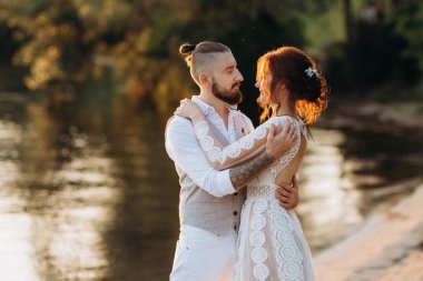 Gelin kız ve damat gün batımında nehrin kenarında