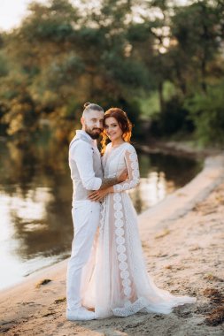 Gelin kız ve damat gün batımında nehrin kenarında
