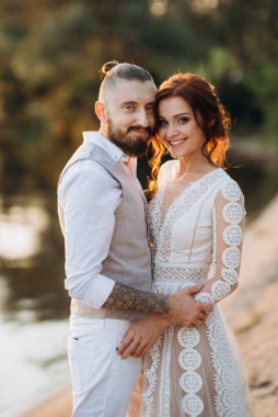 Gelin kız ve damat gün batımında nehrin kenarında