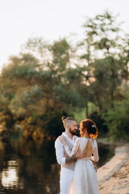 Gelin kız ve damat gün batımında nehrin kenarında