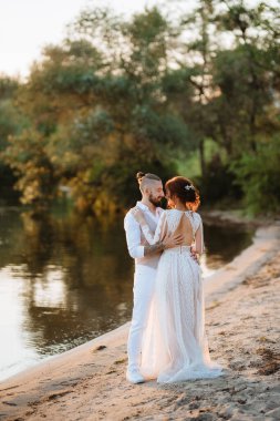 Gelin kız ve damat gün batımında nehrin kenarında