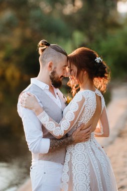 Gelin kız ve damat gün batımında nehrin kenarında