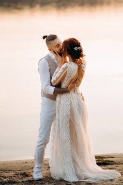 Gelin kız ve damat gün batımında nehrin kenarında