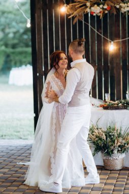 Gelin ve damadın ilk düğün dansı gün batımında restoranın içinde.