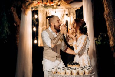 newlyweds happily cut, laugh and taste the wedding cake