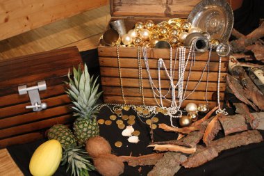 Ahşap bir kutu, mücevherler, inciler, ruhlar, meyve, ananas, tabaklar, ahşap paralar,