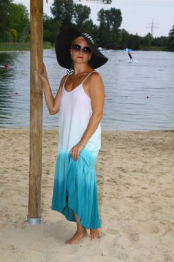 Portrait of an attractive lady in a hat in a beach dress on the beach