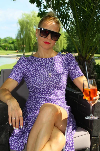 stock image Portrait of an attractive woman with a drink of Aperol, sitting in a beach lounge