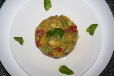 Ceviche 'ye yakın, vegan yemeği, mango, domates, avokado, chili, limon karışımı, beyaz bir tabakta servis edilir.,