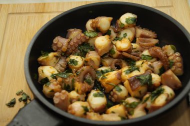 close up of a pan with seafood, tubes, squid, herbs,