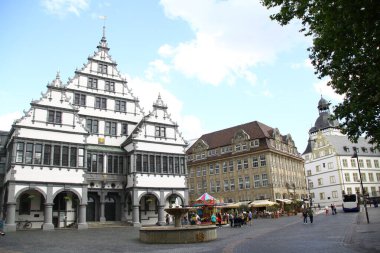 paderborn, nrw, germany, july seventh, 2021, people strolling on the town hall square with town hall, bistro bar celona and gymnasium theodorianum in the background, clipart