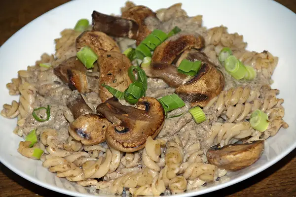 Mantarlı İtalyan makarnası, mantar ve taze soğandan yapılan krema sosu, beyaz bir tabakta servis edilir.