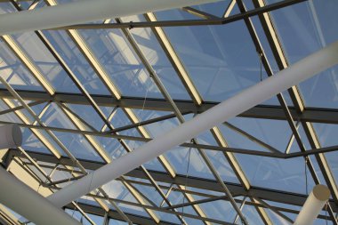 Cam ve çelikten yapılmış grafik çatı yapısı, ışıkla dolu.