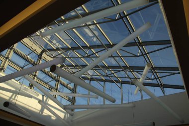 Cam ve çelikten yapılmış grafik çatı yapısı, ışıkla dolu.