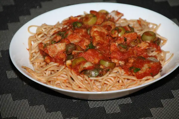 Makarnanın spagetti, balık, kapari, zeytin, domates, domates sosu ve bitkilerle yakın çekimi,