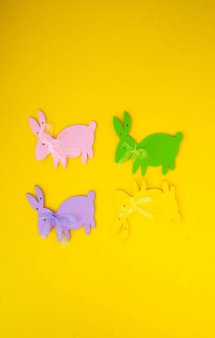 Sarı arka planda Paskalya süslemesi. Renkli kağıt tavşanlar..