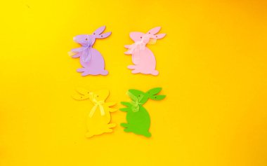 Sarı arka planda Paskalya süslemesi. Renkli kağıt tavşanlar..