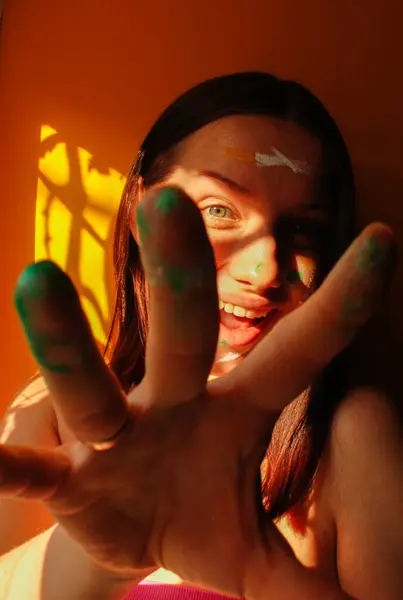 Gün ışığında yüzünde boya olan genç bir kızın portresi.