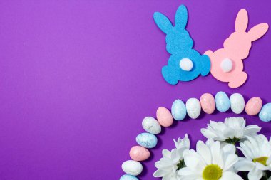 Yumurtalı, tavşanlı ve mor arka planda çiçekli Paskalya süslemesi..
