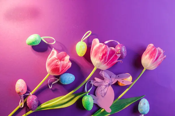 Paskalya yumurtaları ve mor arka planda laleler. Üst görünüm.