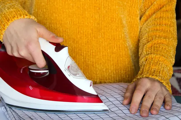 Kız giysileri ütülüyor. Ev hayatı. Vücut parçası