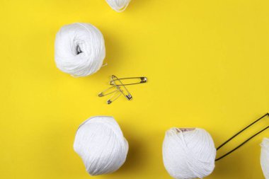Sarı arka planda beyaz iplik ve örgü aksesuarları var. Mesaj için yer var. İş konsepti