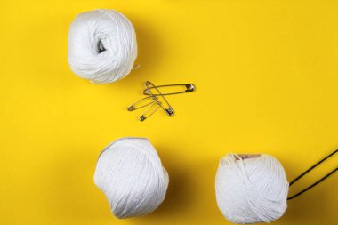 Sarı arka planda beyaz iplik ve örgü aksesuarları var. Mesaj için yer var. İş konsepti