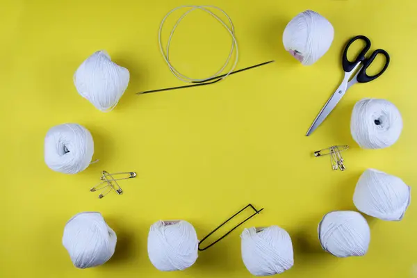 Sarı arka planda beyaz iplik ve örgü aksesuarları var. Mesaj için yer var. İş konsepti