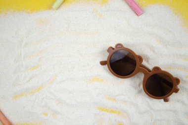 Kumlu arka planda çizim için tebeşirle çevrili çocuk gözlükleri uzanıyor. Plaj, yaz, tatil kavramı