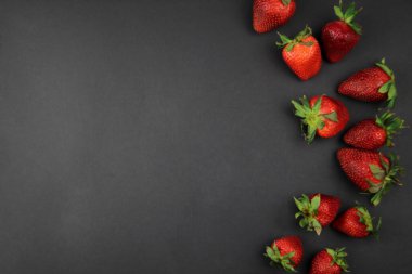 Çemberin siyah arka planında sulu bir çilek bulunur. Çilek. Mesaj için yer var. Sağlıklı beslenme ve çiftlik yemekleri..