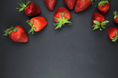 Siyah arka planda sulu bir çilek yatıyor. Çilek. Mesaj için yer var. Sağlıklı beslenme ve çiftlik yemekleri..