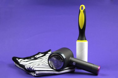 Beyaz çizgili bir üst mor bir arka planda yatar, yanında bir iplik makinesi ve giysi silindiri vardır. Temizlik kıyafetlerini önemseme kavramı.