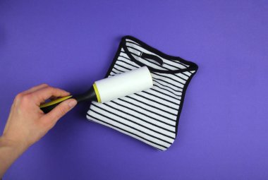 Katlanmış tişörtü temiz tutmak için giysi silindiri kullanan bir kadın eli.