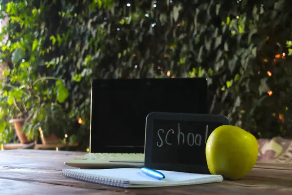 Okul konseptine geri dönelim. Masanın üzerinde bir dizüstü bilgisayar ve okul tabelası var..