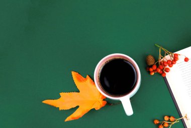 Yeşil arka planda, akçaağaç yaprakları ve Rowan 'ın yanında bir fincan kahve duruyor.