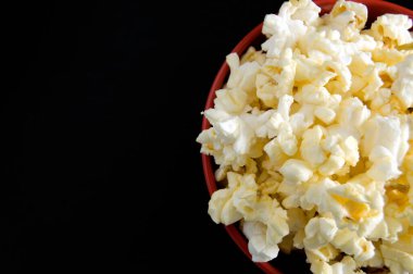 Tereyağlı patlamış mısırın en iyi görüntüsünü siyah kasede izole edilmiş kırmızı kasede kapat