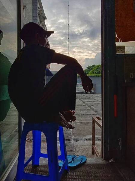 man sitting on a chair in front of the house