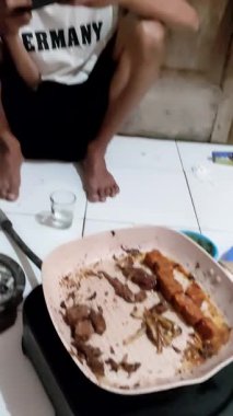 Genç Asyalı adam masada otururken muz yiyor ve cep telefonu kullanıyor.