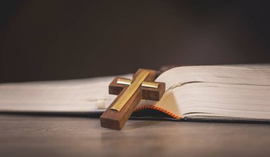 Kitap ve haç tahta bir masada.