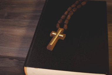 Kitap ve haç tahta bir masada.