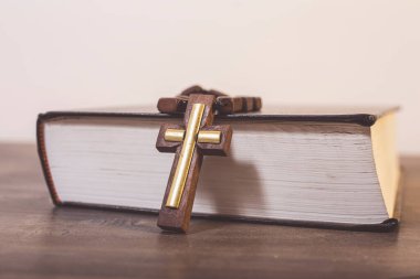 Kitap ve haç tahta bir masada.