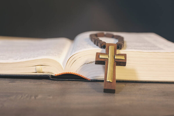 Book and cross on a wooden table