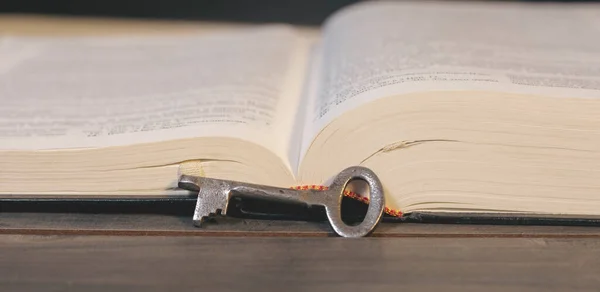 stock image Metal key and book on wooden table