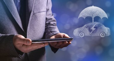 Elektrikli araba ve ağdaki şemsiye. Elinde tablet tutan bir adam.